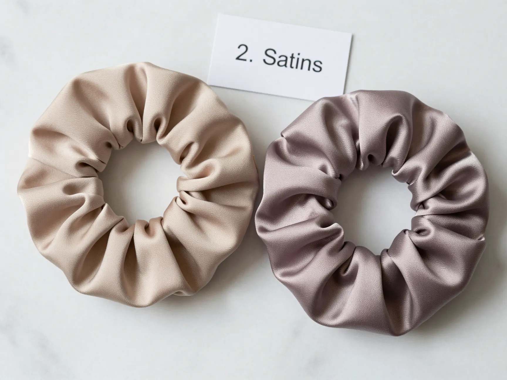 Satin scrunchie comparison with silk on marble surface studio product shot