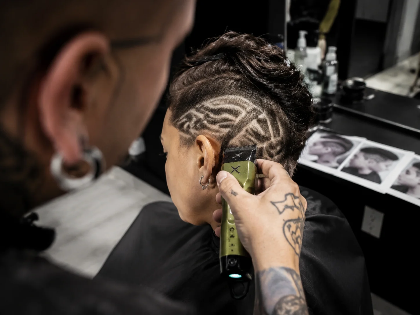 A barber etching a geometric line design into a short undercut