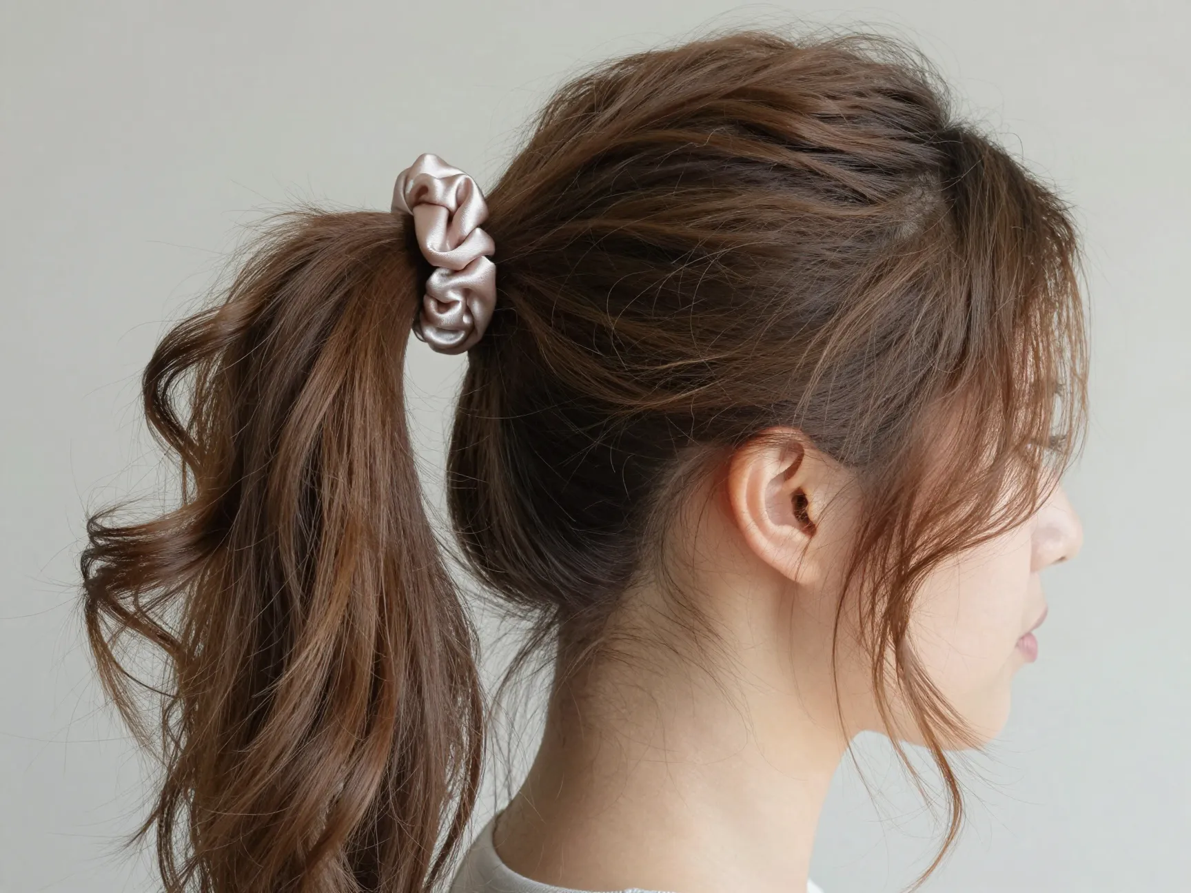 Modern intentional messy ponytail with satin scrunchie and framing curls