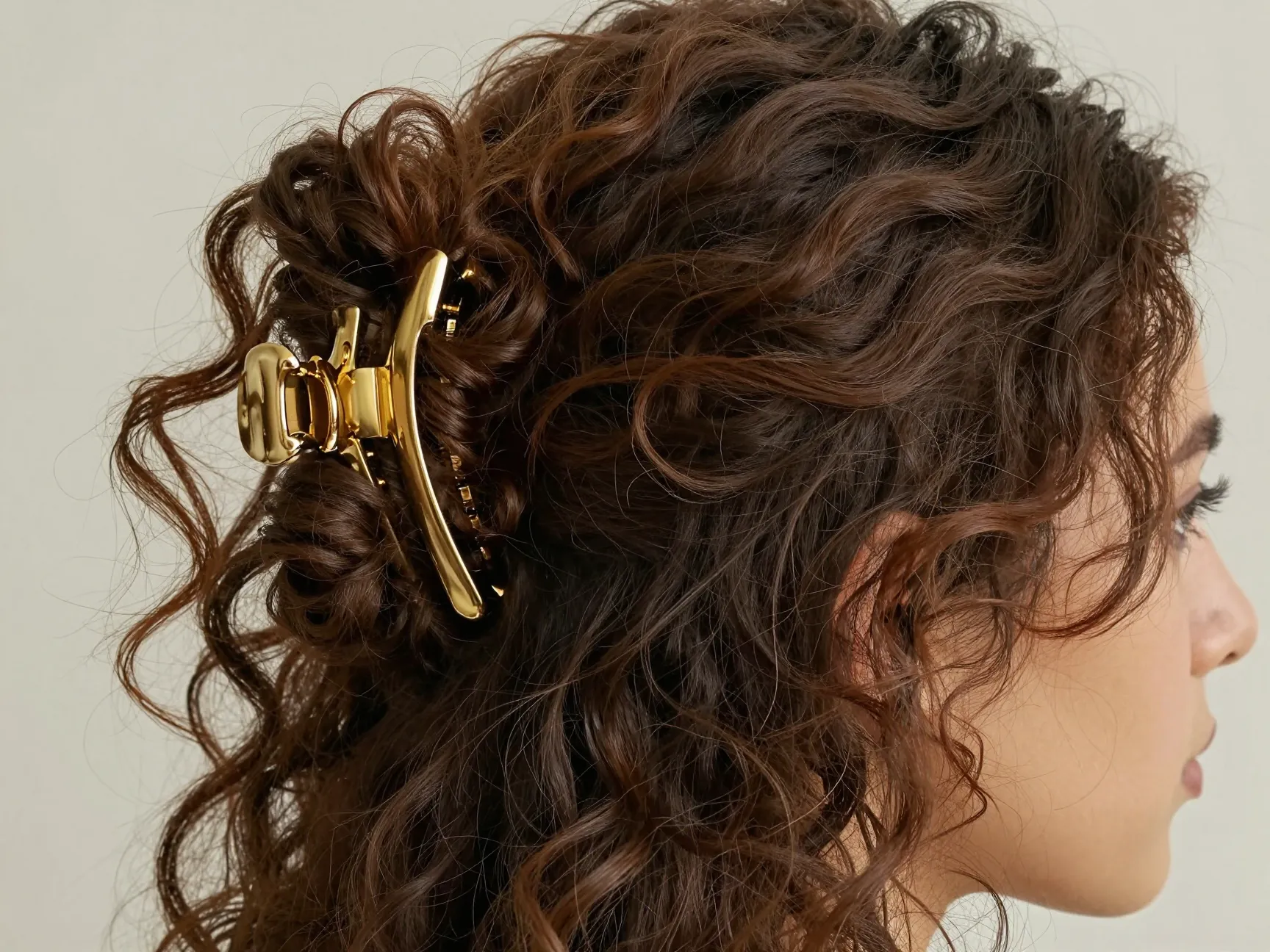 A large gold claw clip holding a loose twisted bundle of curly hair