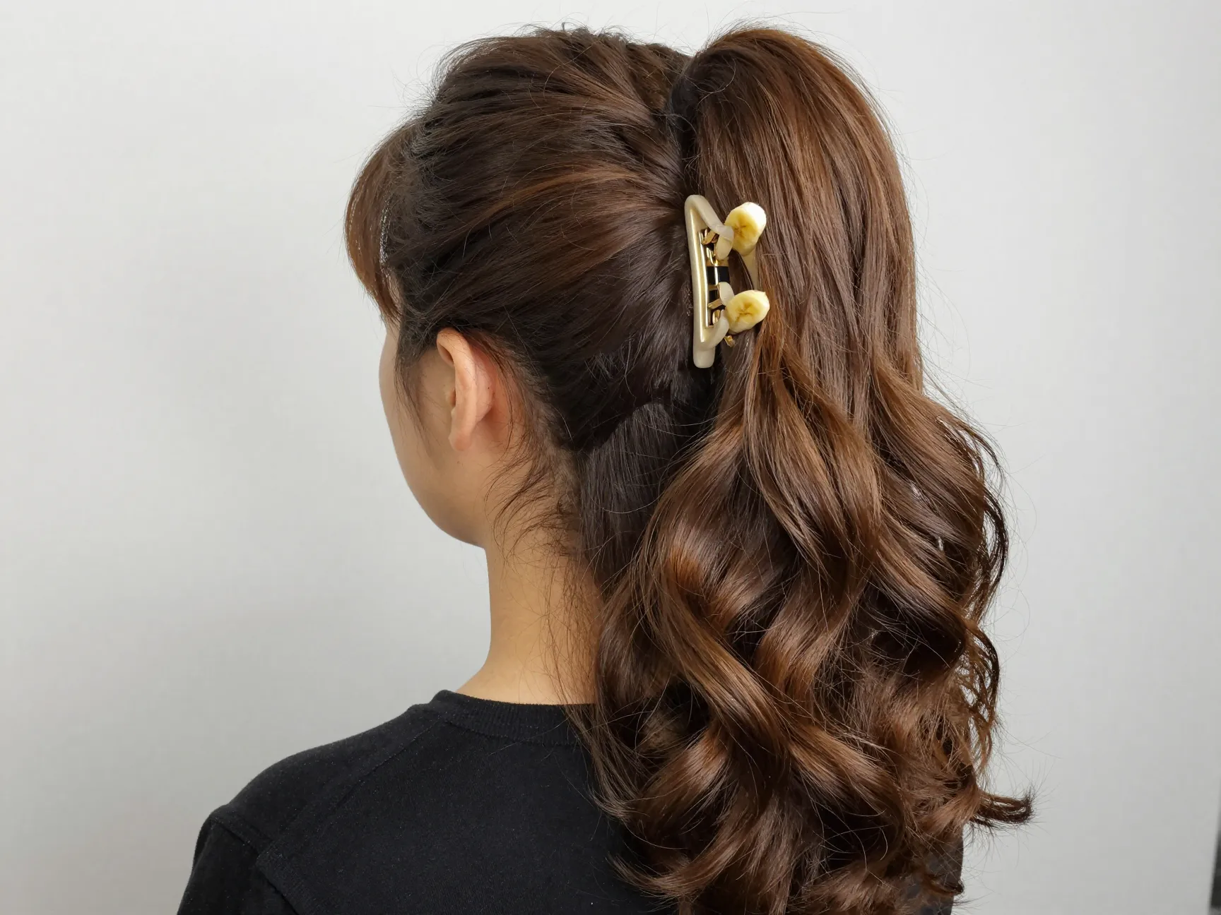 Banana clip creating voluminous cascading brunette ponytail