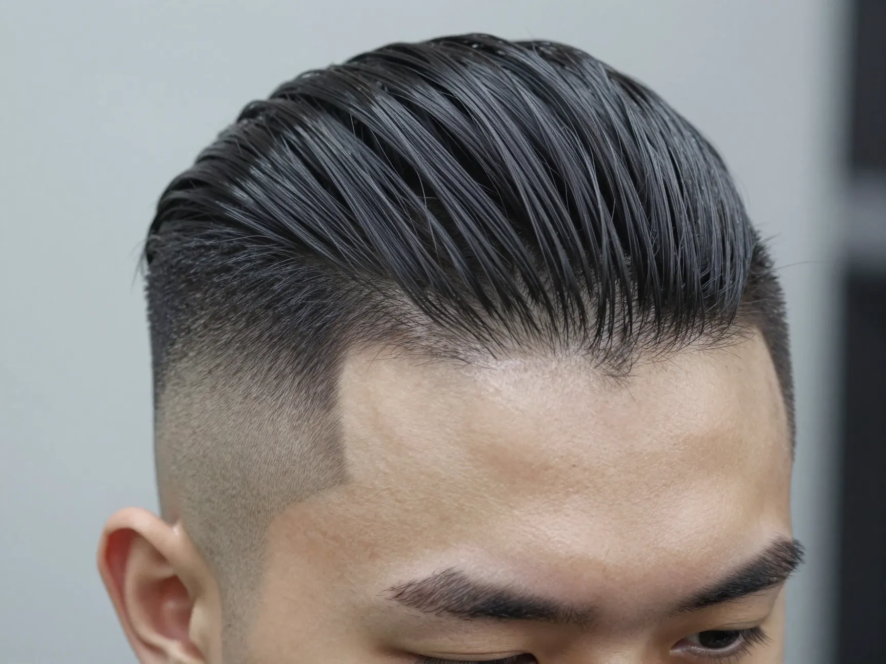 Slick back with a hard shaved line at the temple