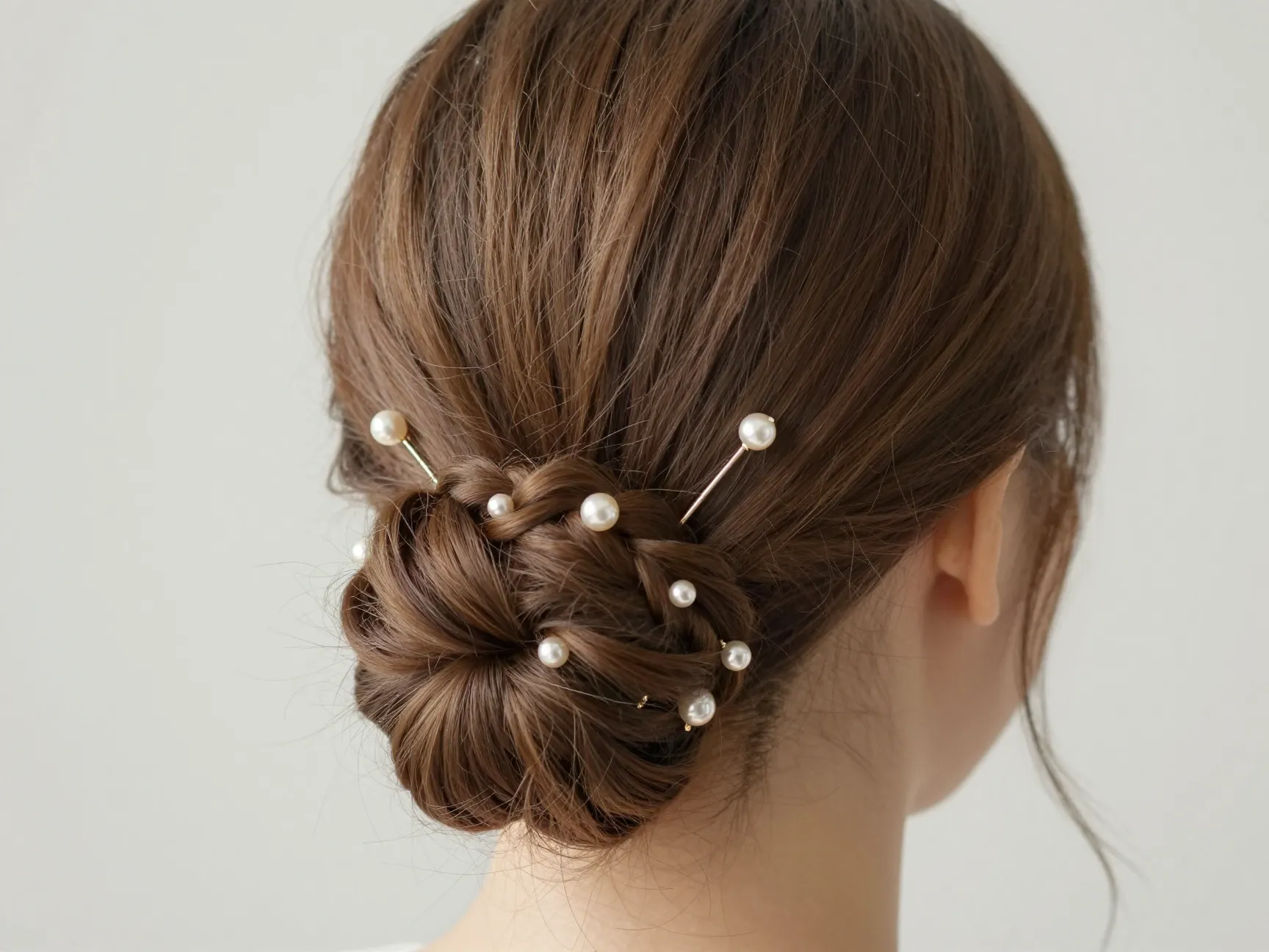 Bun with an incorporated small braid and decorative pearl hairpins