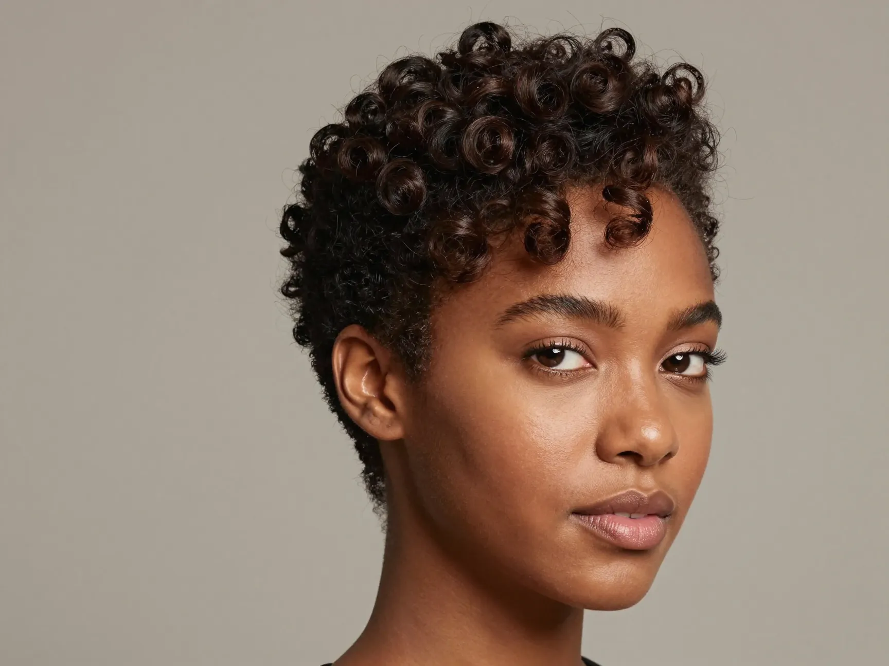 Close cropped pixie cut with defined crown curls and styled edges