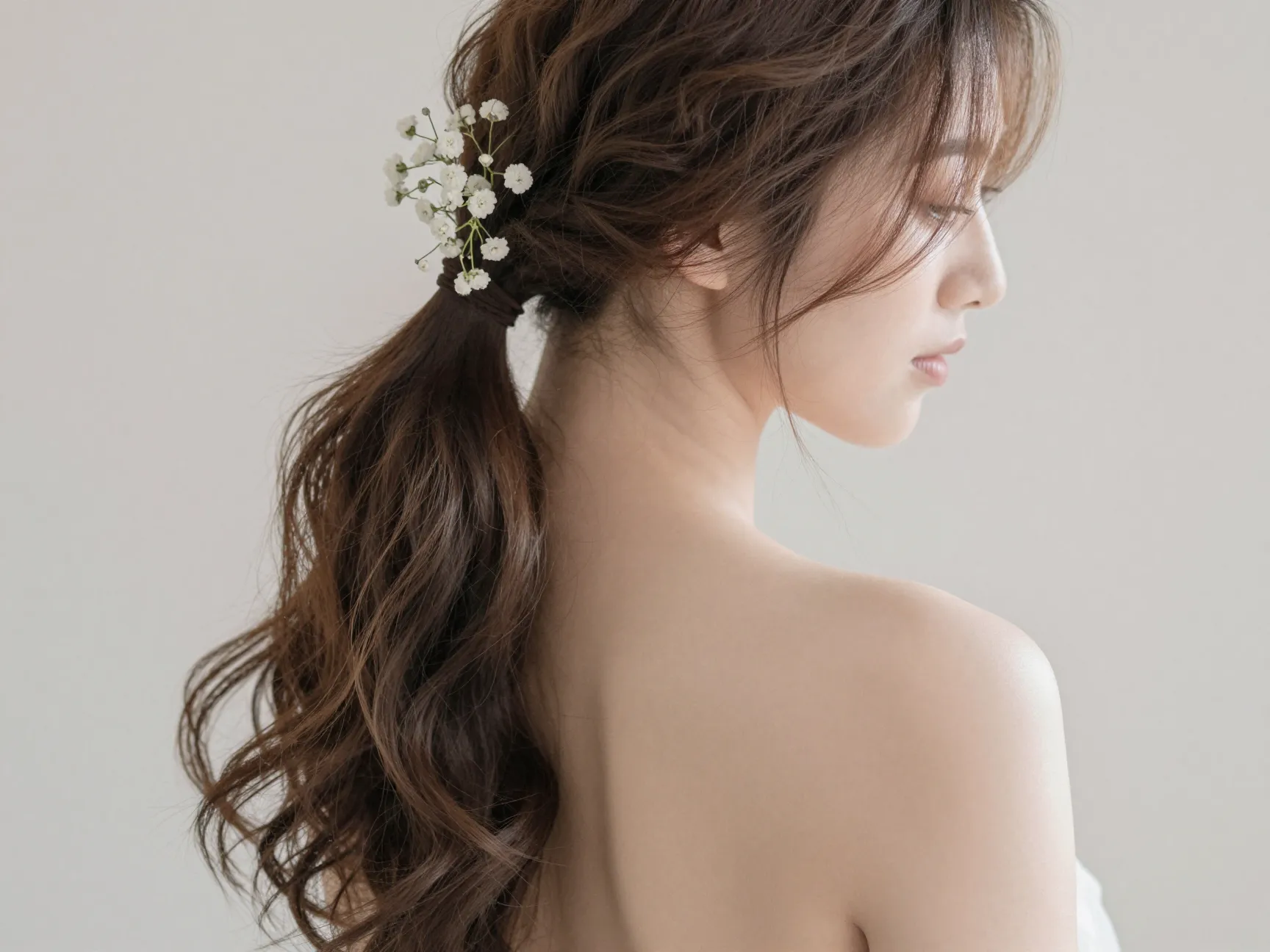 Romantic side ponytail with loose waves over one shoulder for a wedding