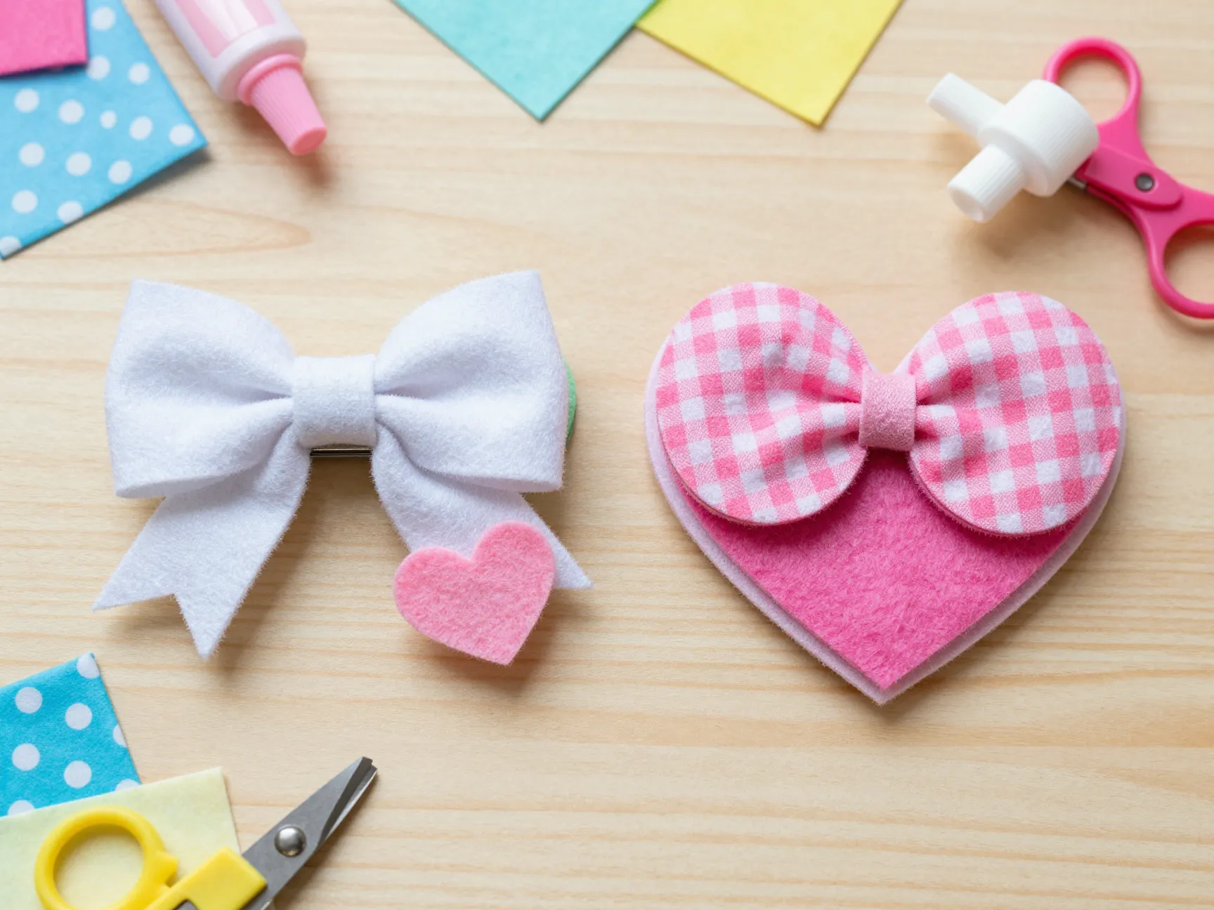 Layered fabric felt bow heart alligator clips on light wood crafting table