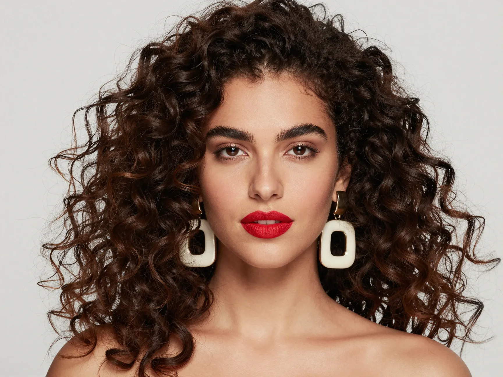 Confident voluminous natural curls with statement earrings and bold lip