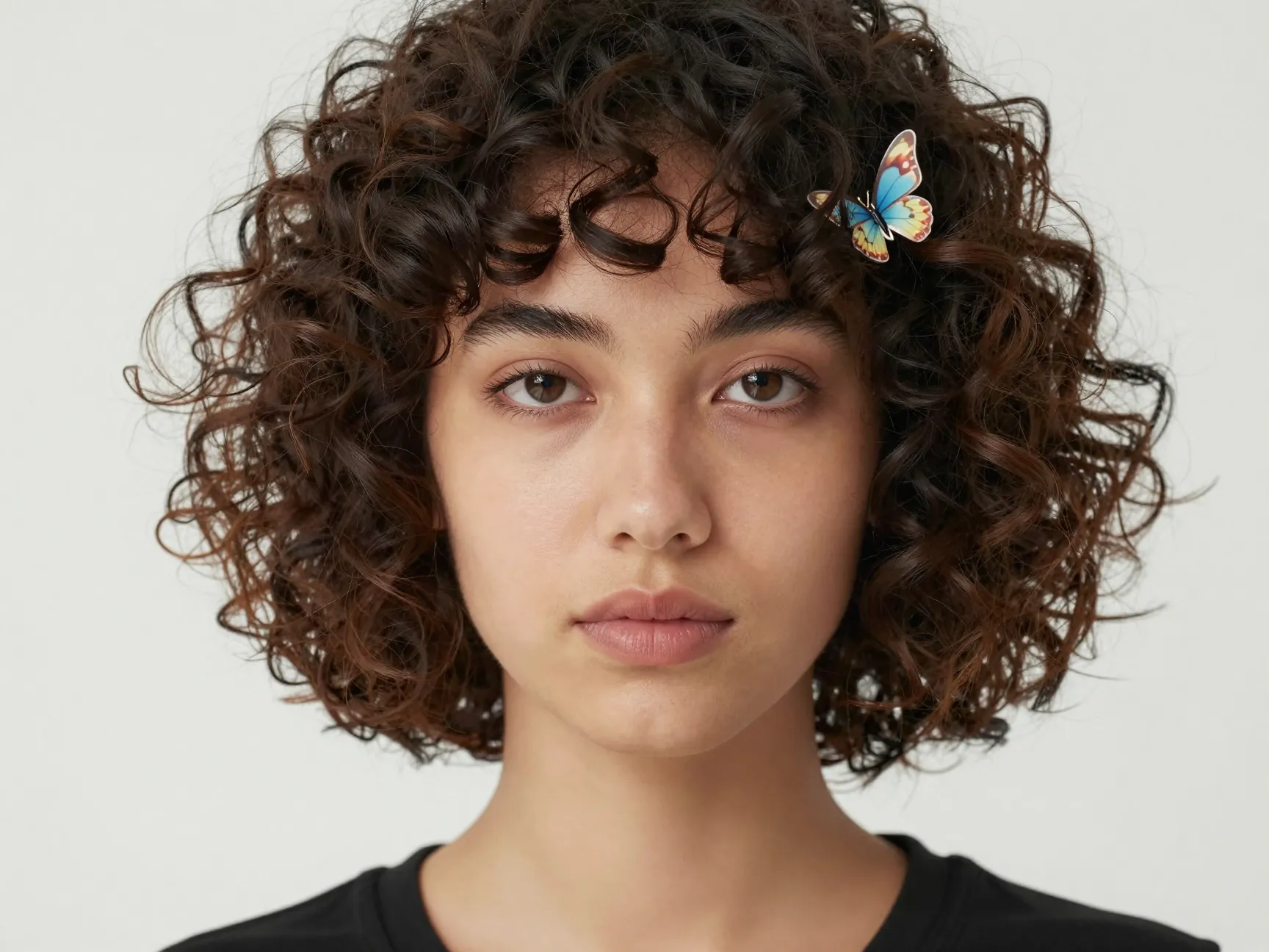 Curly bob haircut at chin length with defined ringlets and a barette