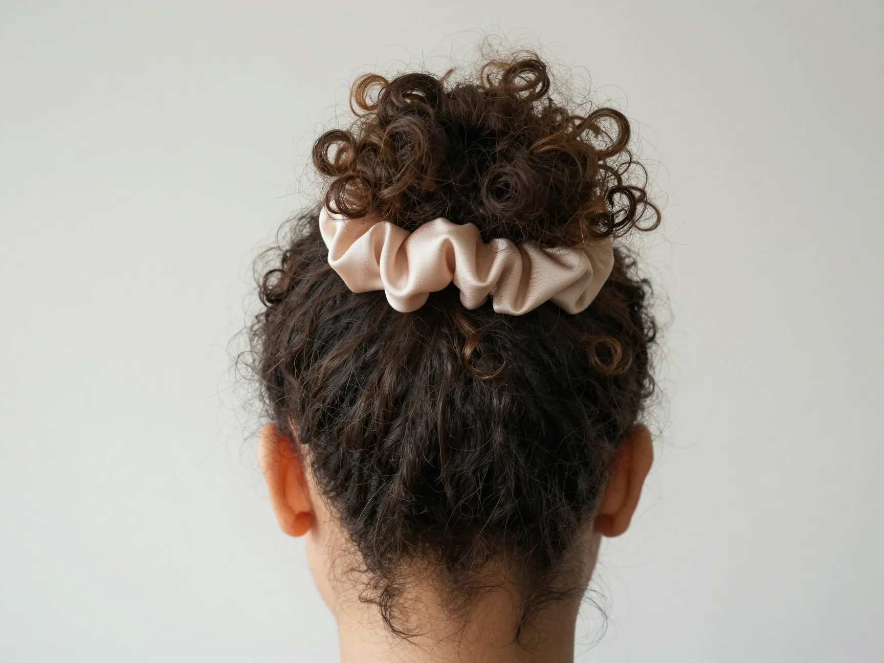 Pineapple updo curls loosely with silk scrunchie