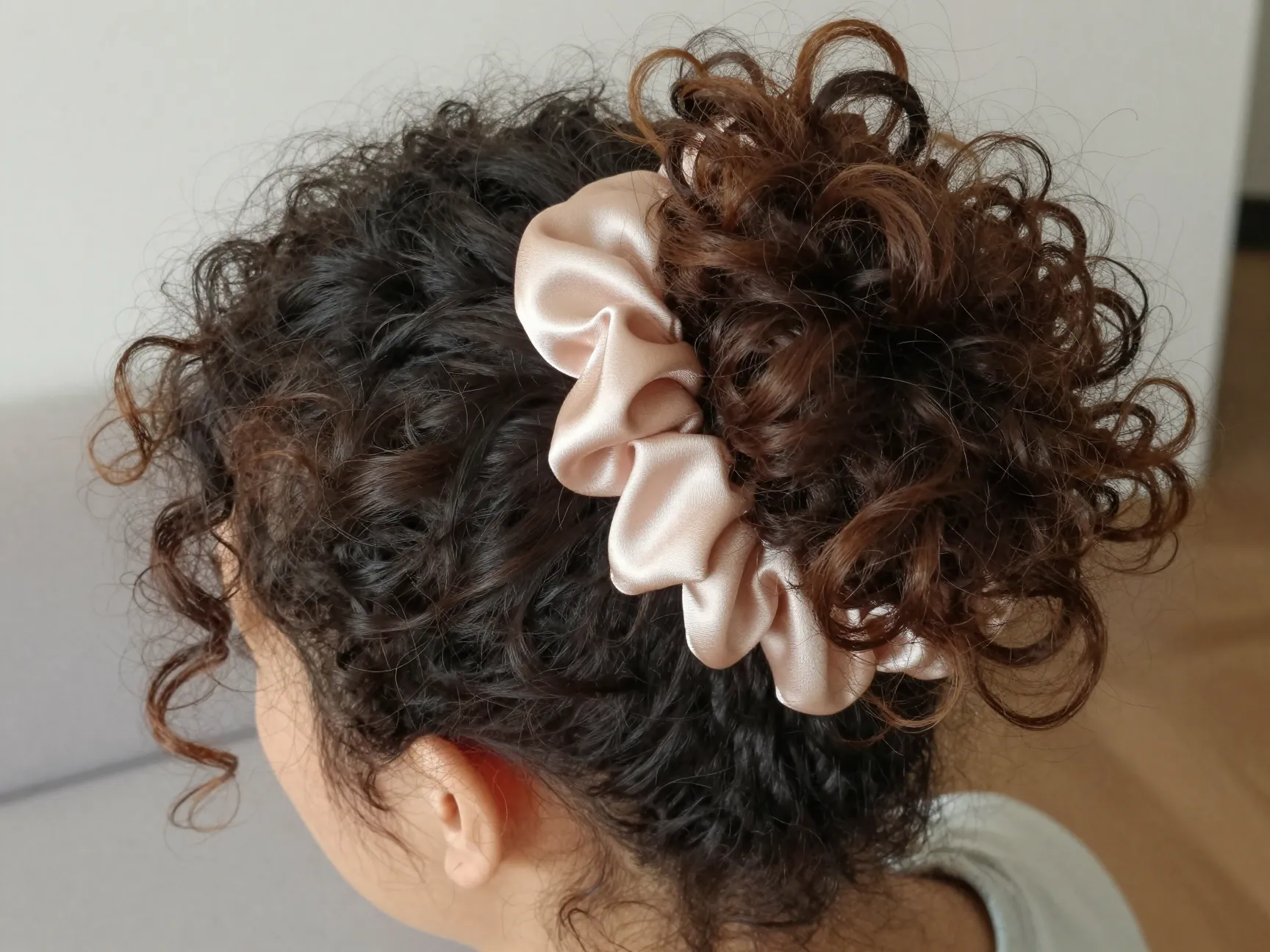 Loose pineapple updo on medium length curly hair with satin scrunchie