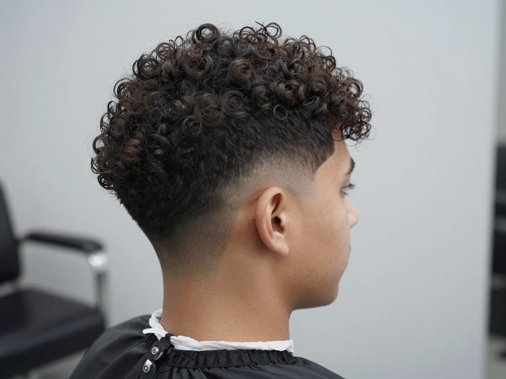 Structured curly fade with full crown and tapered nape