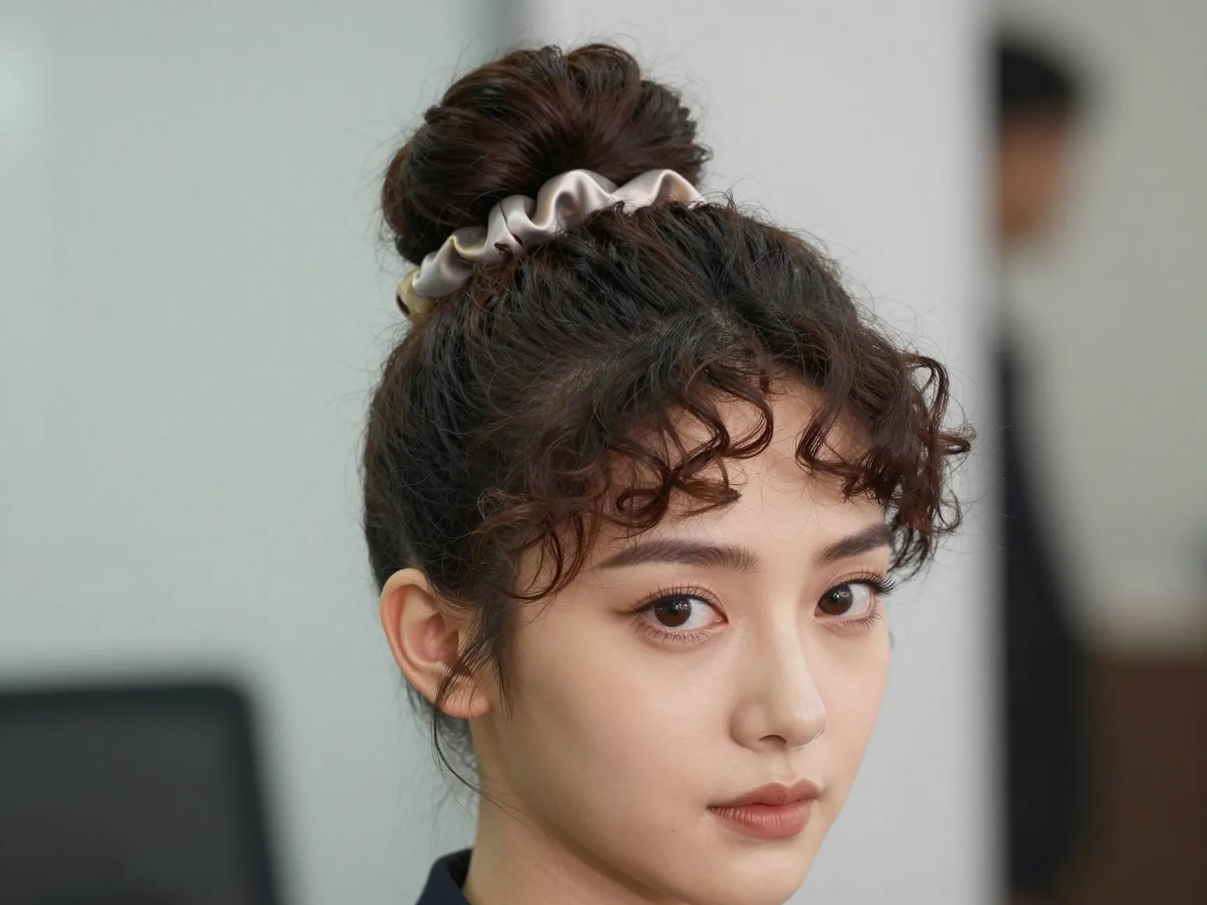 Classic high bun for formal office with face framing curly tendrils