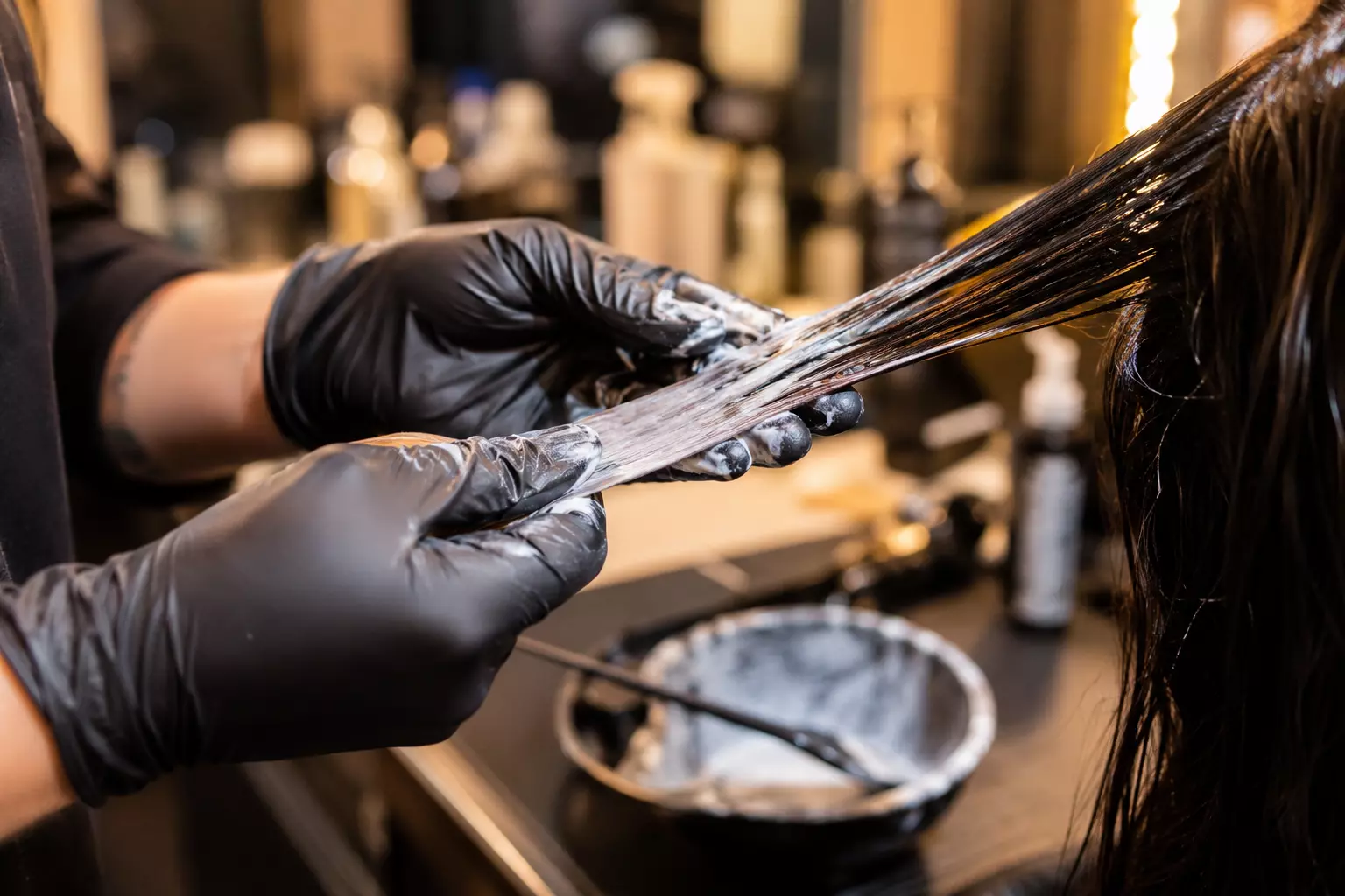 Hairstylist applying hair dye remover strand salon closeup