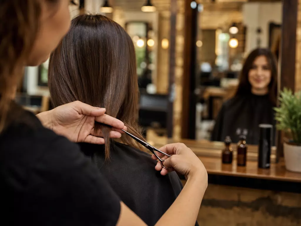 Hairstylist trimming split ends salon mirror candid landscape